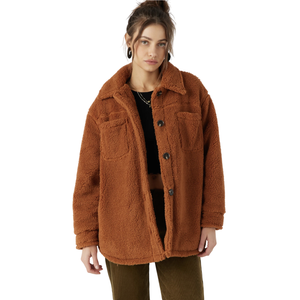 A woman wearing an oversized brown sherpa jacket with button closures, two front pockets, and dark pants.