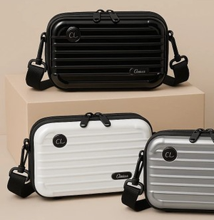Three mini hardside crossbodies are shown: one black, one white, and one silver. Each bag features a ribbed design, a black strap, and small logos with the initials \“CL\“ and the word \“Classic.\“