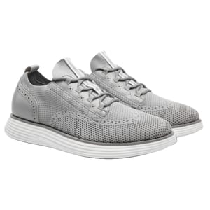 Gray athletic shoes with a knit texture, featuring lace-up design and perforated accents, on a white cushioned sole.