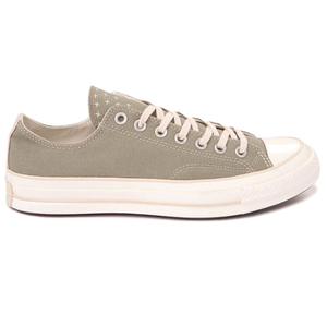 A khaki-colored low-top canvas sneaker with off-white laces and a rubber sole, featuring small white cross details on the tongue.