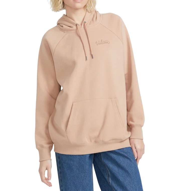 A person wears a beige hooded sweatshirt with \“Volcom\“ embroidered on the front, paired with blue jeans.