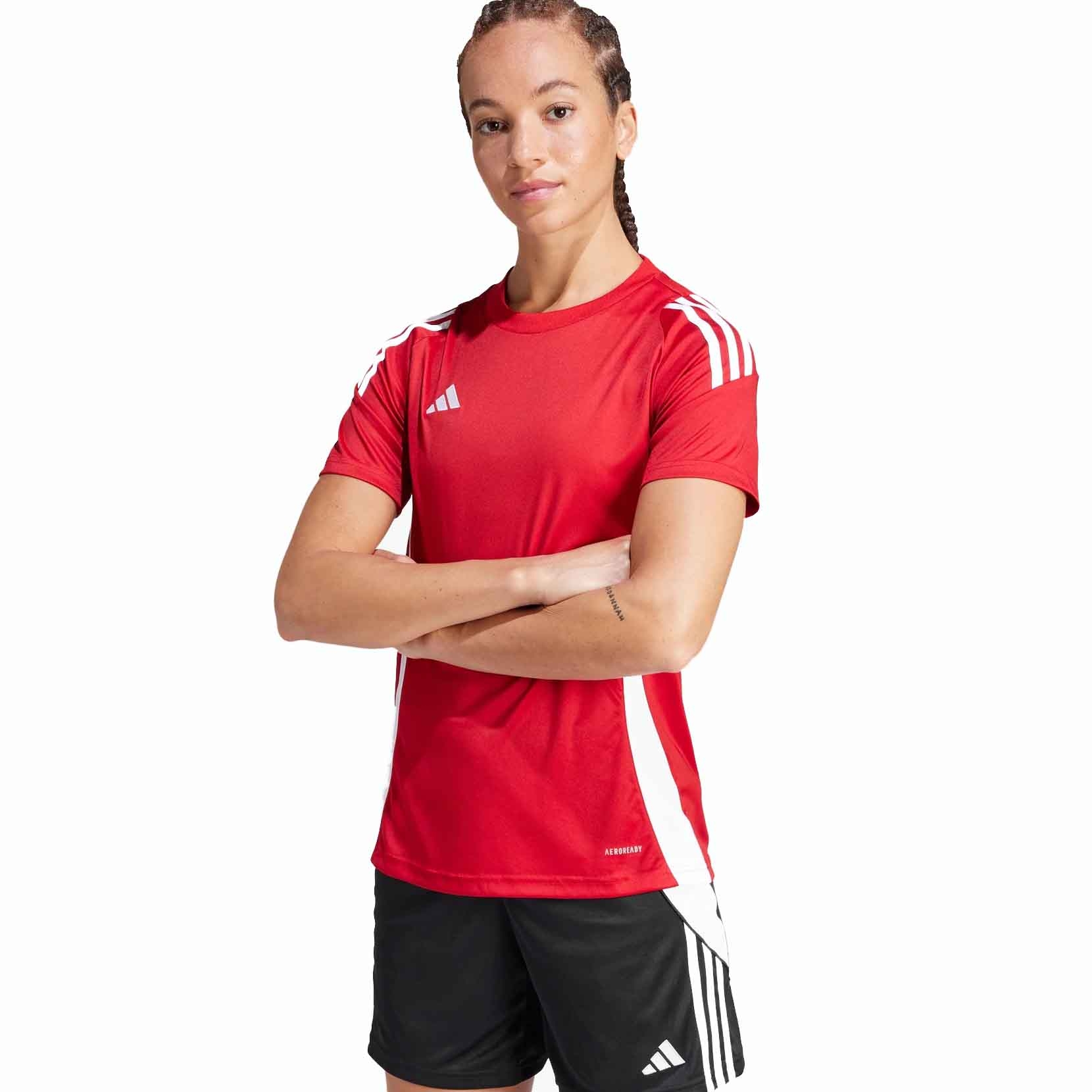 A person is wearing a red Adidas sports jersey with white stripes and the logo, paired with black Adidas shorts featuring white stripes.