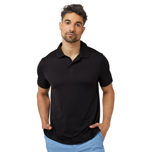 A man is wearing a black short-sleeve polo shirt with blue pants, set against a plain gray background.