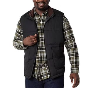 A man is wearing a black Big & Tall puffer vest over a plaid shirt, featuring a zippered front and side pockets.
