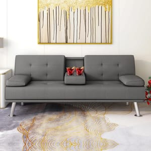 Gray futon sofa bed with a split back design, featuring two removable armrests and a center fold-down console with cup holders. The sofa stands on metallic legs and is placed on a decorative rug with a gold line pattern.