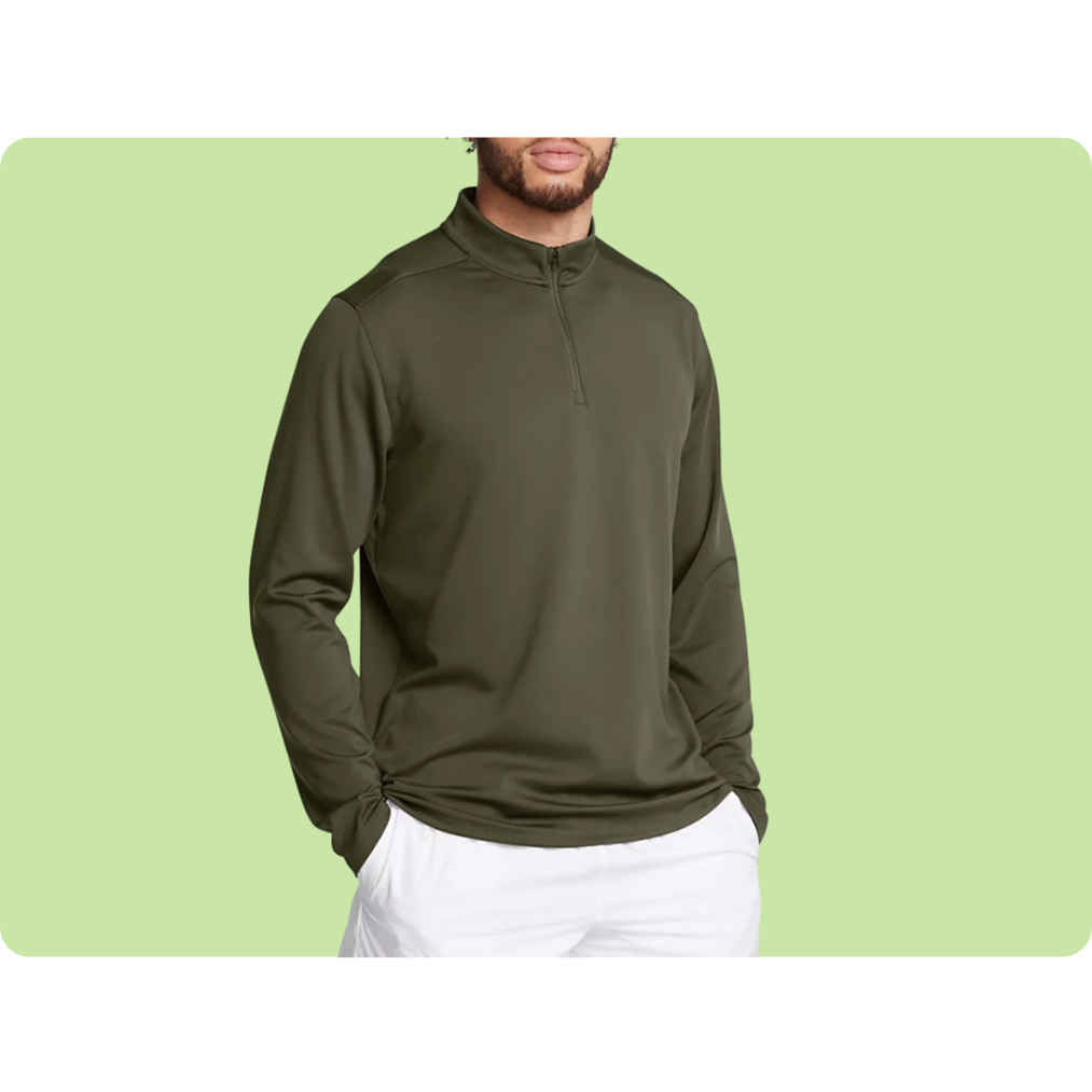 A person is wearing a long-sleeve, olive green, half-zip pullover sweater paired with white pants against a light green background.