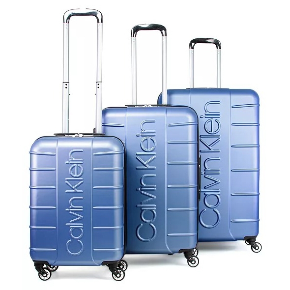 Set of three blue Calvin Klein hard-shell suitcases with telescopic handles and four-wheel spinners, featuring embossed branding.