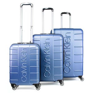 Set of three blue Calvin Klein hard-shell suitcases with telescopic handles and four-wheel spinners, featuring embossed branding.
