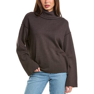 A dark-colored funnel neck sweatshirt with dropped shoulder seams and long sleeves, paired with light blue jeans.