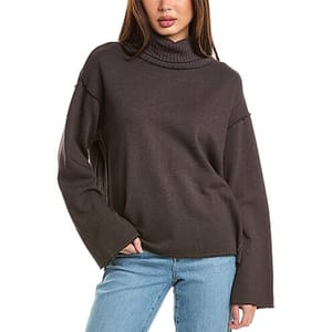 A dark-colored funnel neck sweatshirt with dropped shoulder seams and long sleeves, paired with light blue jeans.