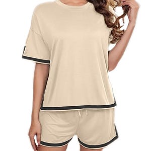A beige two-piece lounge set comprising a short-sleeve, round-neck top and drawstring shorts, both accented with contrasting black trim.