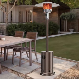 48,000 BTU patio heater with a sleek metallic finish, flame visible under a large reflector dome, and equipped with wheels for easy mobility, positioned on a stone patio alongside outdoor dining furniture.