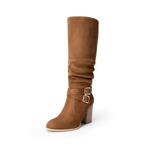 These are knee-high women's boots in a tan color, featuring a rounded toe, chunky heel, and two decorative buckles at the ankle.