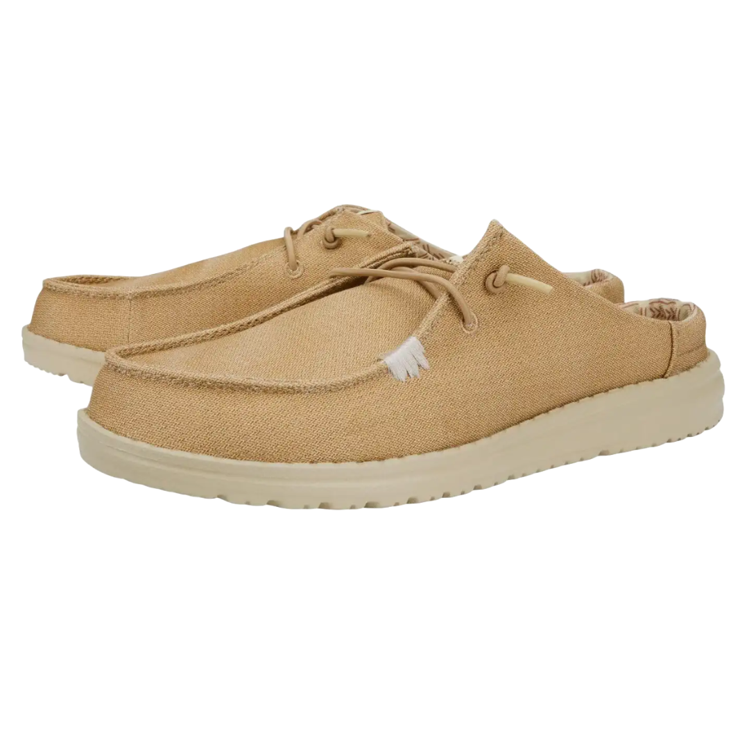 Hey Dude Wendy Slip-Ons are tan slip-on shoes with a low back, featuring a lightweight fabric upper, cushioned sole, and lace-up detail for a casual look.