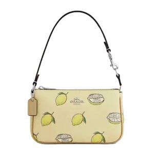 A small Coach handbag featuring a lemon motif on a light yellow background with a detachable black strap.