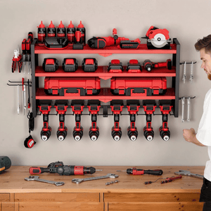 A mounted tool organizer holds red and black power tools, battery packs, bottles, and accessories, with various hand tools on hooks. A workbench below is scattered with wrenches and drills.