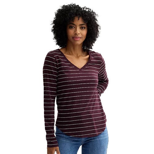 A woman is wearing a maroon and white striped V-neck long-sleeve shirt paired with blue jeans.