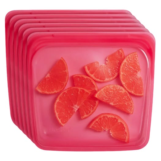 A stack of reusable red silicone storage bags, each with slices of citrus fruit inside, likely depicting food storage or preservation.