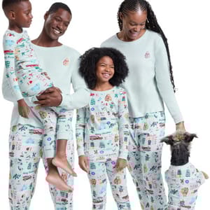 Family wearing matching holiday-themed pajamas, including a man, woman, two children, and a small dog. Bright, festive designs with a variety of holiday symbols are featured on their outfits.