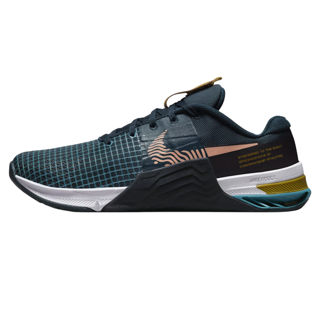 A dark blue athletic shoe with a grid pattern, featuring a graphic swoosh and the text \“Engineered to the exact specifications of championship athletes\“ on the side. It has a textured sole with layered colors and a woven loop on the tongue.