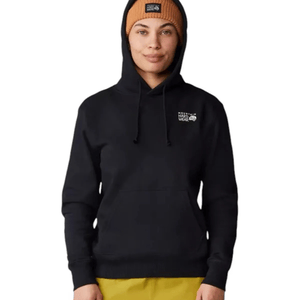 A person wears a black Mountain Hardwear hoodie and a tan beanie, both featuring the brand's logo. They are also wearing yellow pants.