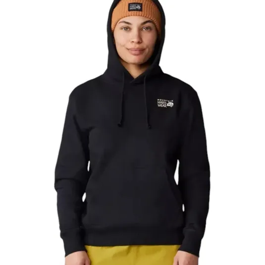 A person wears a black Mountain Hardwear hoodie and a tan beanie, both featuring the brand's logo. They are also wearing yellow pants.