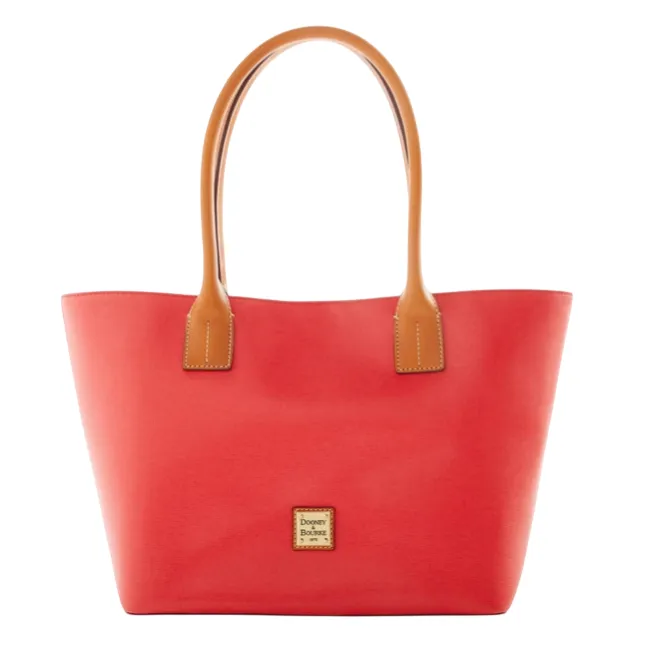 A red tote bag with tan handles featuring a small, centered logo plaque on the front.