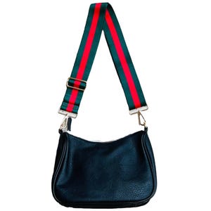 A black leather purse features a detachable strap with green and red stripes. The strap is adjustable and attached with metal clips, providing a sporty and stylish accent to the bag.