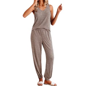 A woman is wearing a two-piece loungewear set consisting of a sleeveless V-neck top and matching relaxed-fit pants, paired with white slide sandals.