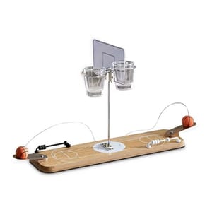 The Hammer + Axe Basketball Drinking Game features a mini wooden basketball court with a hoop and two shot glasses. Players use a launcher to shoot small basketballs into the glasses, combining elements of basketball and drinking games.