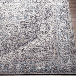 A 9' x 12' machine-washable area rug featuring a vintage-inspired design with a mix of blue, gray, and cream tones, showcasing intricate floral and medallion patterns on a bordered edge.