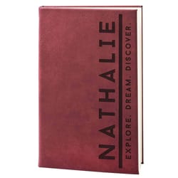 A burgundy notebook with the name \“Nathalie\“ in large vertical letters and the phrase \“Explore. Dream. Discover.\“ written horizontally.