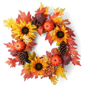 A decorative wreath featuring artificial fall foliage, such as red and yellow leaves, sunflowers, small pumpkins, and pine cones. The wreath measures 23 inches across.