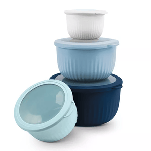 A stack of four plastic storage bowls with lids in varying shades of blue and one white, featuring a ribbed texture, used for food storage.