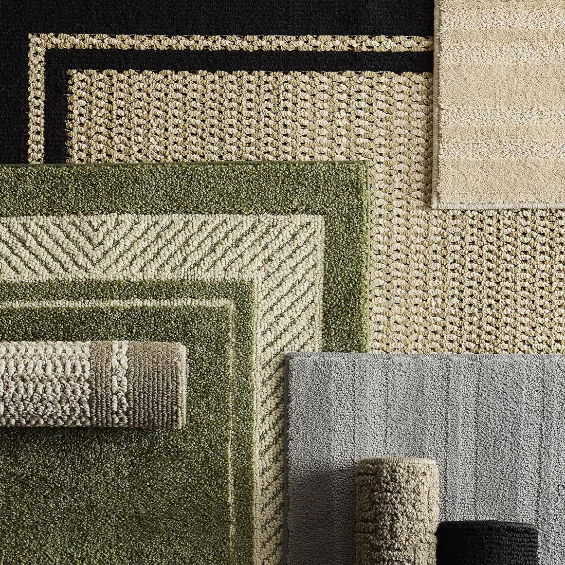 Various textured rugs in earthy tones of green, beige, and gray are displayed, some rolled and some flat, showcasing different patterns and border designs.