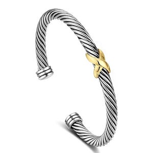 A stylish cuff bracelet featuring a twisted metal design in silver tone with a central gold-tone knot accent, open-ended for easy wear.