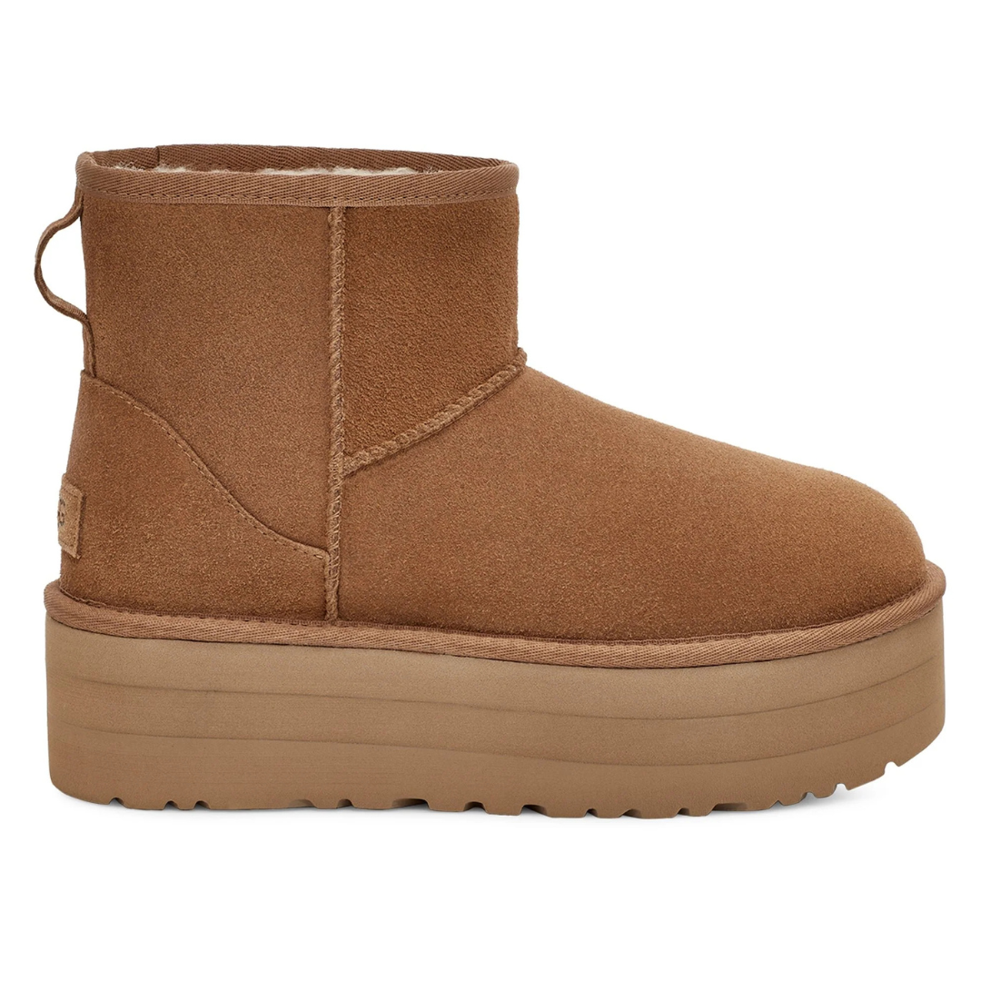 UGG Classic Mini Platform Boots in chestnut color feature a short ankle height, plush suede exterior, and thick platform sole for added height and style. They include a pull tab at the back and are designed for comfort and warmth.