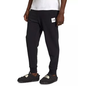 Black North Face men's joggers with a logo patch on the left thigh, featuring a slim fit and cuffed ankles.
