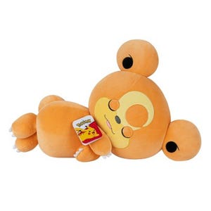 A plush toy of the Pokémon Teddiursa, featuring a round orange body with closed eyes, lying on its side. A tag with the Pokémon logo and Pikachu is attached.