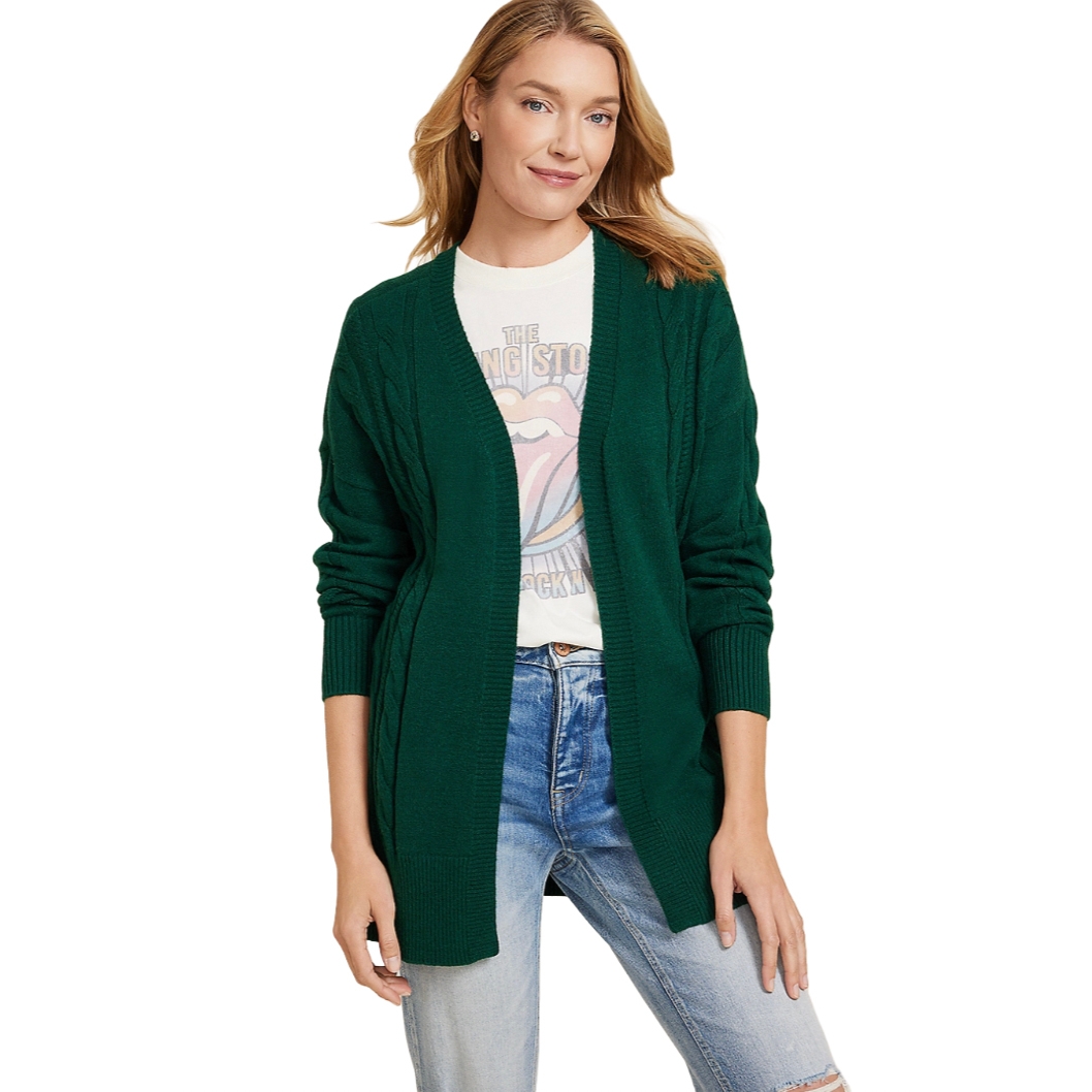 A woman is wearing a green cardigan over a graphic T-shirt that features a band logo, paired with light blue jeans.