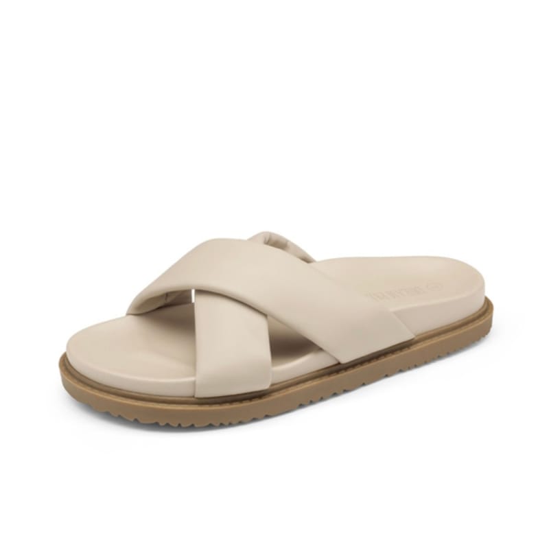 A single beige slide sandal with crisscross straps and a flat sole.