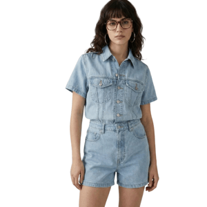 Woman wearing a light blue denim short-sleeve shirt paired with matching high-waisted denim shorts, accessorized with large hoop earrings and glasses.