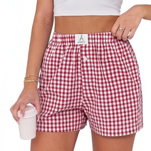 Red and white gingham shorts with an elastic waistband and button detail, paired with a white crop top. The person is holding a small white cup.
