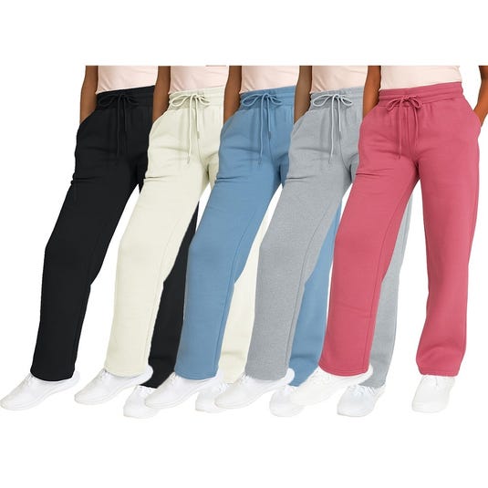 Five pairs of women's sweatpants in black, cream, blue, gray, and pink are displayed, each featuring an elastic waistband with a drawstring and paired with white sneakers.
