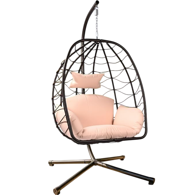 A hanging egg chair with a metal frame and light pink cushions is situated on a patio, surrounded by greenery and palm trees.