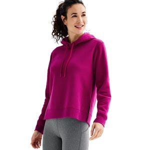 A woman wears a magenta hoodie paired with gray leggings.