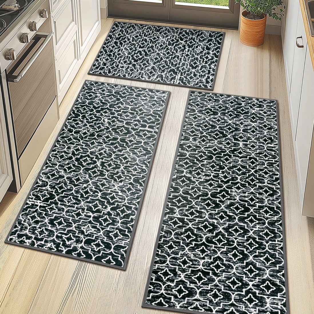 Set of three black and white patterned kitchen rugs with a geometric design arranged on a light wood floor.
