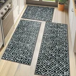 Set of three black and white patterned kitchen rugs with a geometric design arranged on a light wood floor.