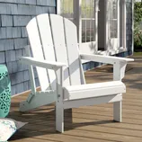 A white Adirondack chair is placed on a wooden deck, accompanied by a turquoise side table and patterned cushion.