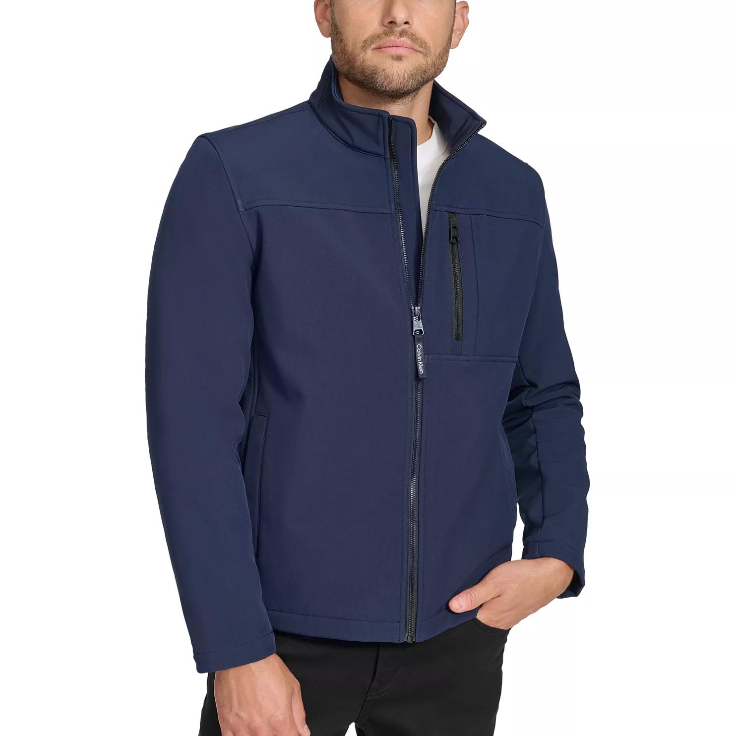 A man is wearing a navy blue zip-up jacket with a standing collar, two side pockets, and a zippered chest pocket, paired with black pants.